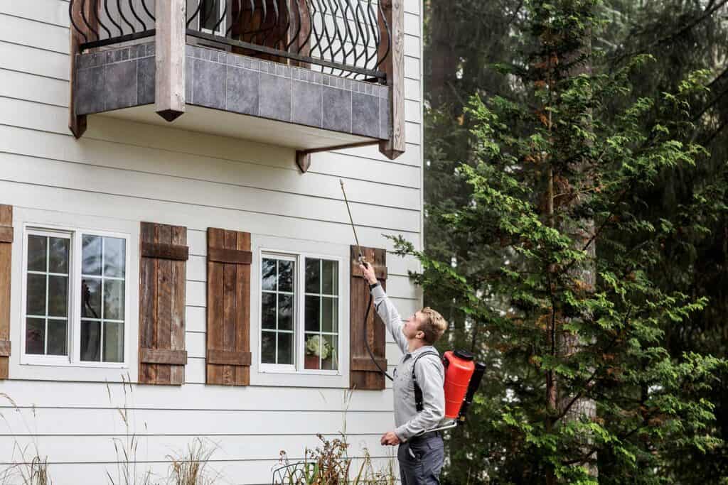 A man spraying a house with a sprayer.